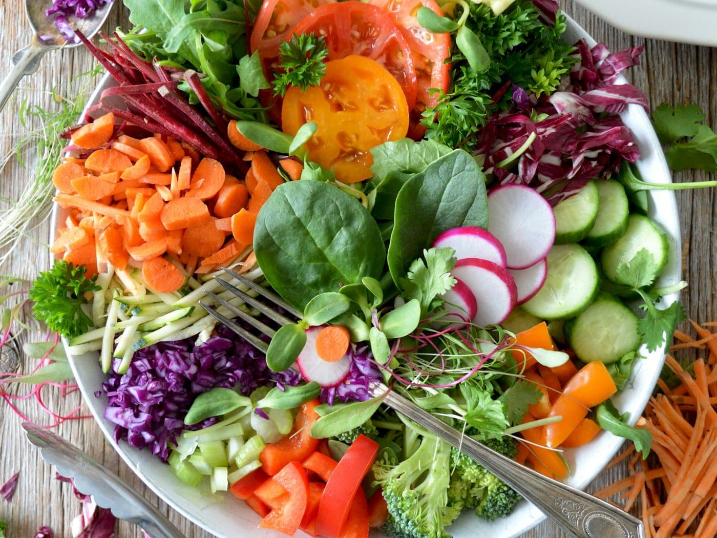 Fresh produce and cuts laid out on a steel prep bench